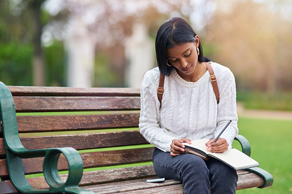 woman on bench journaling | holiday stress tips