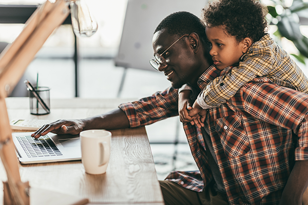 father working while holding son | holiday stress tips