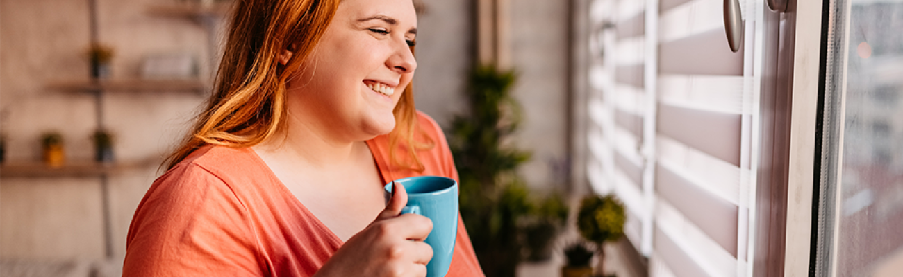 woman drinking coffee while looking out the window | is caffeine bad for you