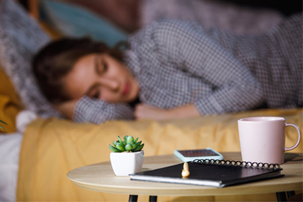 woman sleeping next to journal on nightstand | how to fall asleep faster