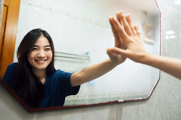 woman high-fiving herself in the mirror | health esteem