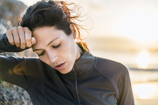 Woman wiping sweat from forehead