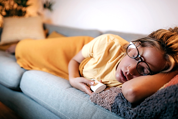 Woman snoozing on couch with TV on