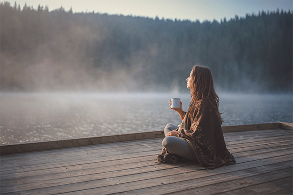 woman drinking coffee on dock | Daily Mantra