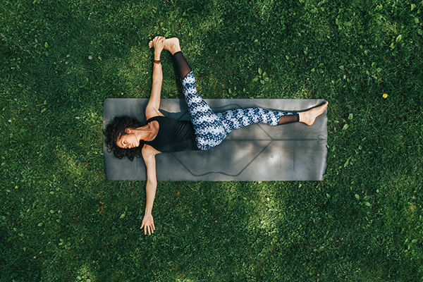 woman doing yoga on grass | Yoga Before or After Workout