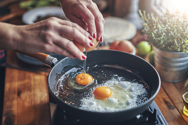 Woman frying eggs in pan