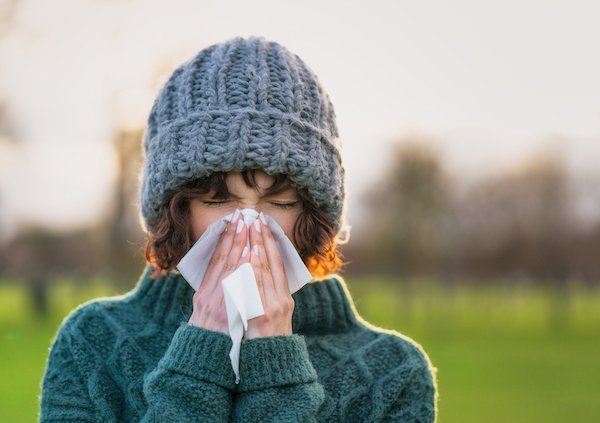 Woman outdoors blowing her nose