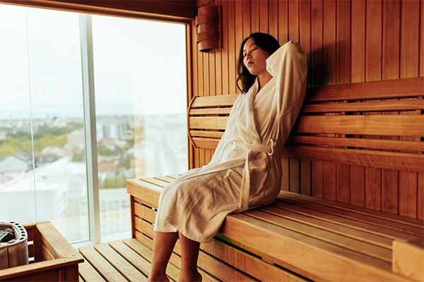 woman massaging her neck in sauna | Sauna Before or After Workout