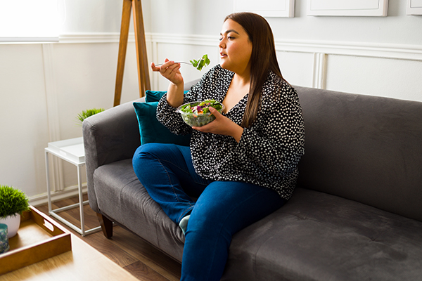 Woman eating salad on couch