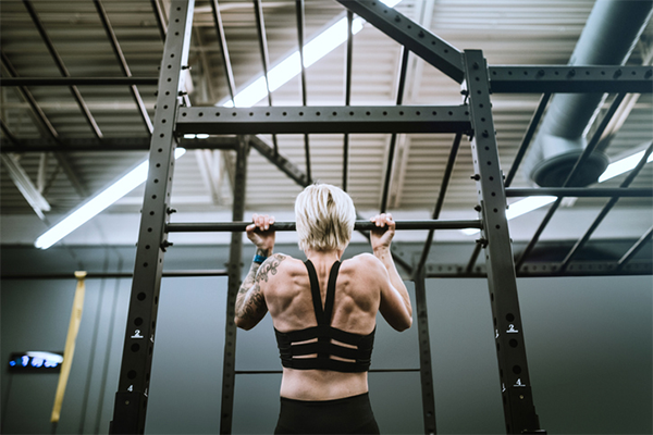 backview of woman doing chin up | Can You Work Out After Getting a Tattoo