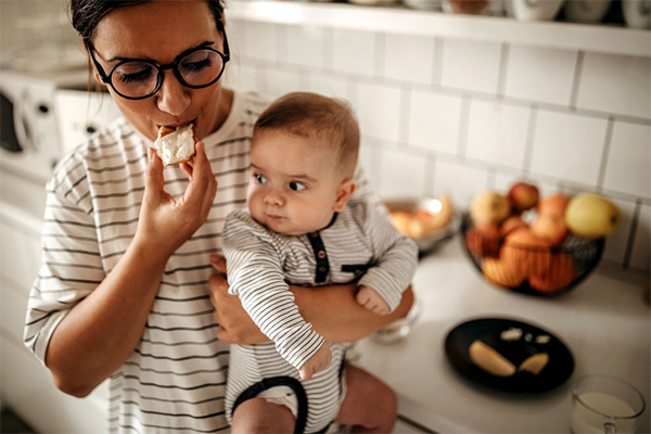 mom eating fruit while holding baby | What to Eat While Breastfeeding