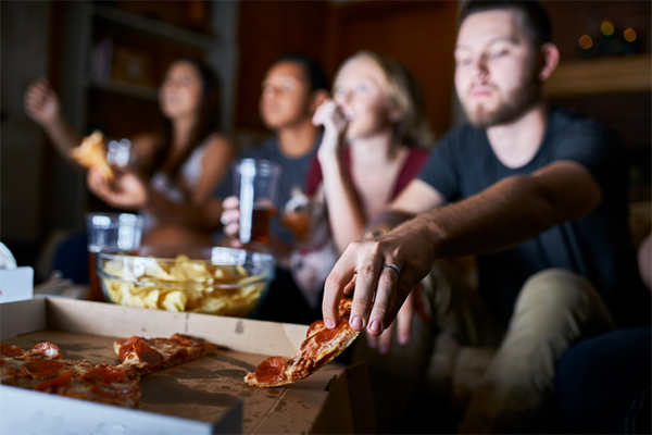 man reaching for another slice of pizza