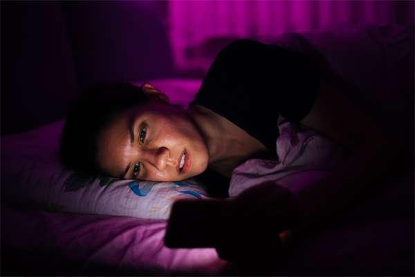 woman staring at phone in bed