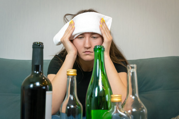 hungover woman staring at empty alcohol bottles | congeners in alcohol