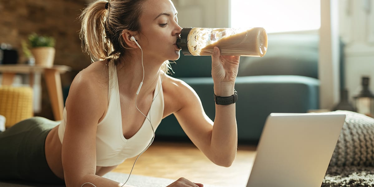 Woman Drinks Shake in Front of Laptop | Benefits of Protein Shakes