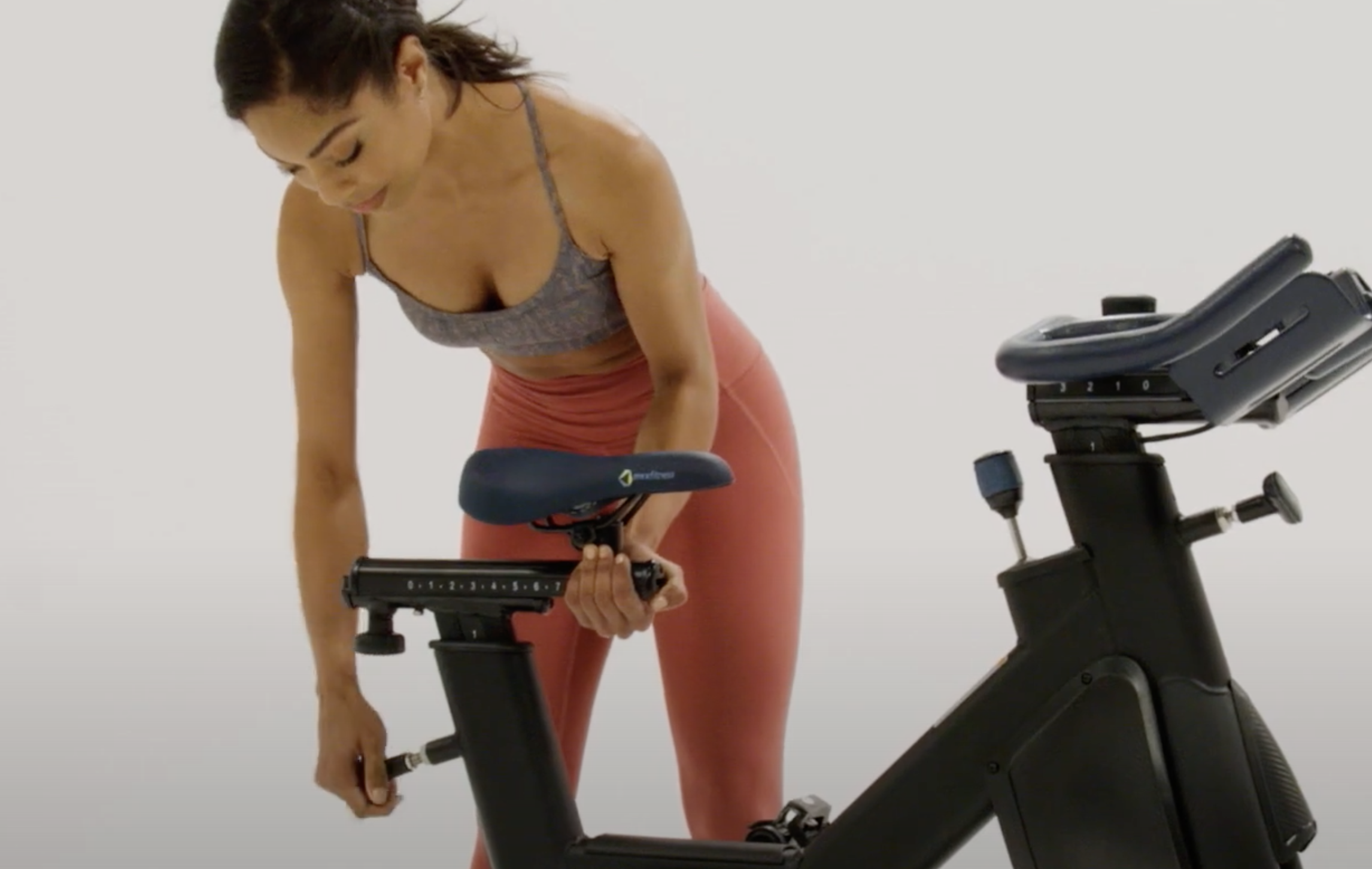 Woman Adjust Seat Height | Indoor Cycling Mistakes