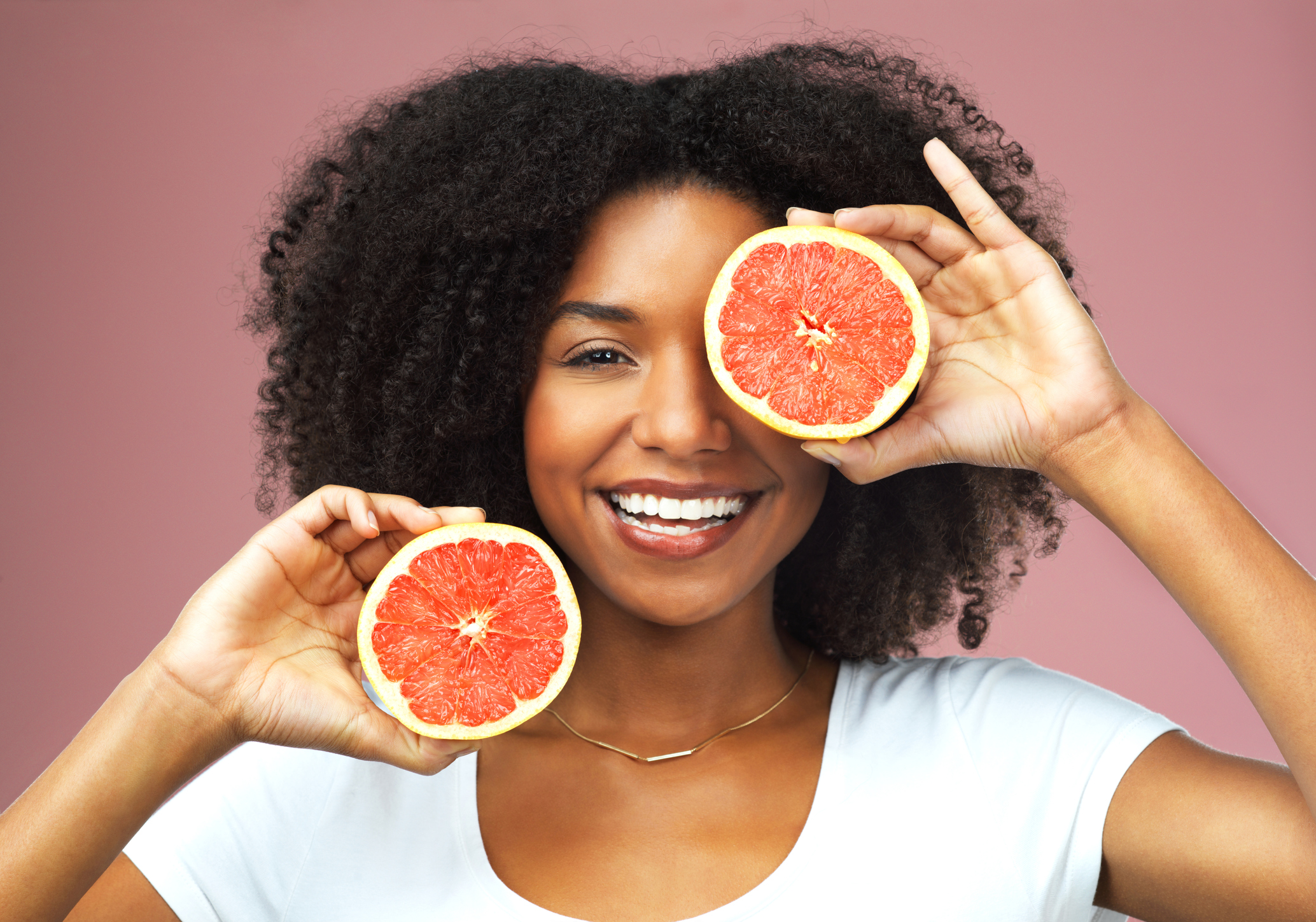 The woman is holding grapefruit in front of her face | Grapefruit diet