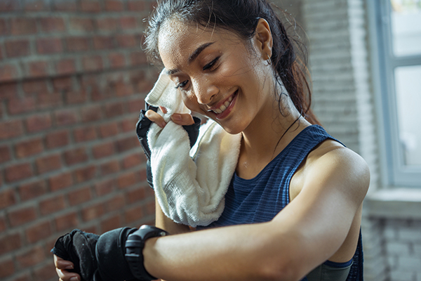 Une femme vérifie son tracker d'activité physique entre les séries | Repos entre les séries