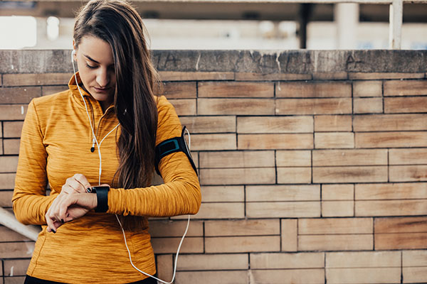 Une femme vérifie son tracker d'activité physique | Musculation vs cardio