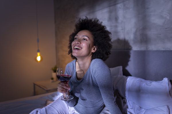 Woman In Bed Enjoying Glass of Wine | Catch Up on Sleep