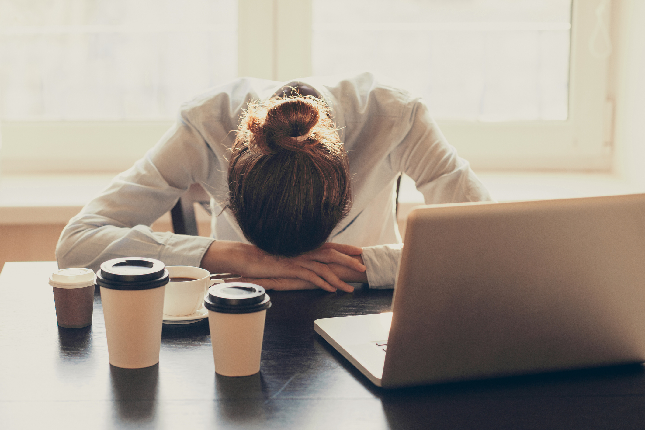 Woman Tired with Several Cups of Coffee in Front of Her | Catch Up on Sleep