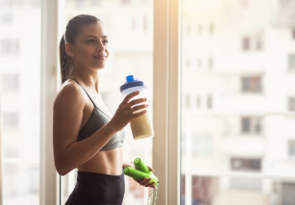 Woman drinks protein shake near window |  Pea Protein Versus Soy Protein