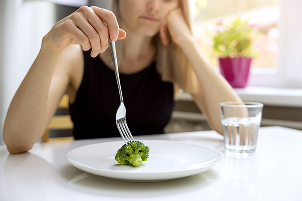 woman picking at broccoli | Orthorexia