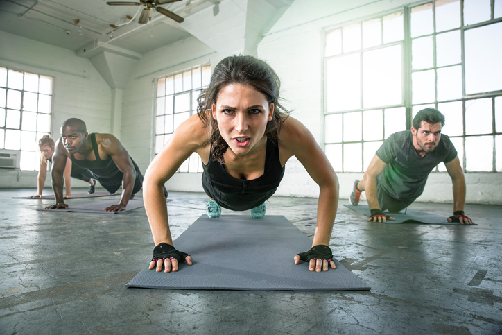 Image of Class Doing Workout with Woman Struggling in Center | Feel the Burn