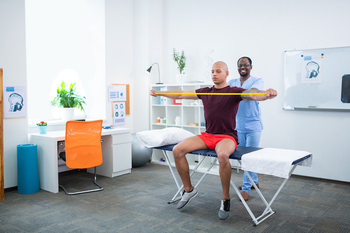 Man using a strip of resistance to stretch with physiotherapy | PNF Stretching