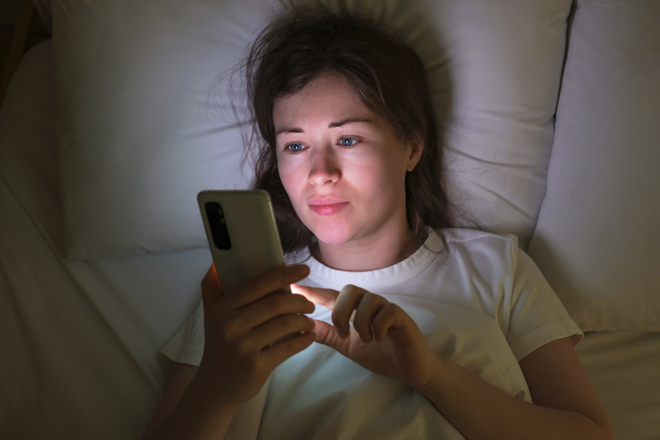 Close Up of Woman on Her Phone in Bed | Sleep Hygiene Tips