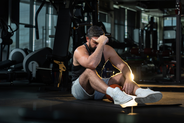 Exhausted man Sits at Gym | how to keep morning workouts from wearing you out