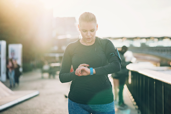 A woman checks the tracker of fitness while running Point theory