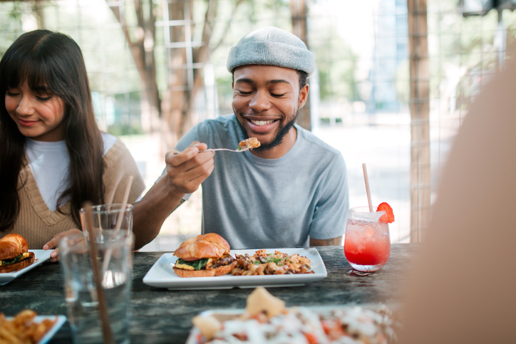 Man eating food with friends | What happens when you stop taking Mounjaro?