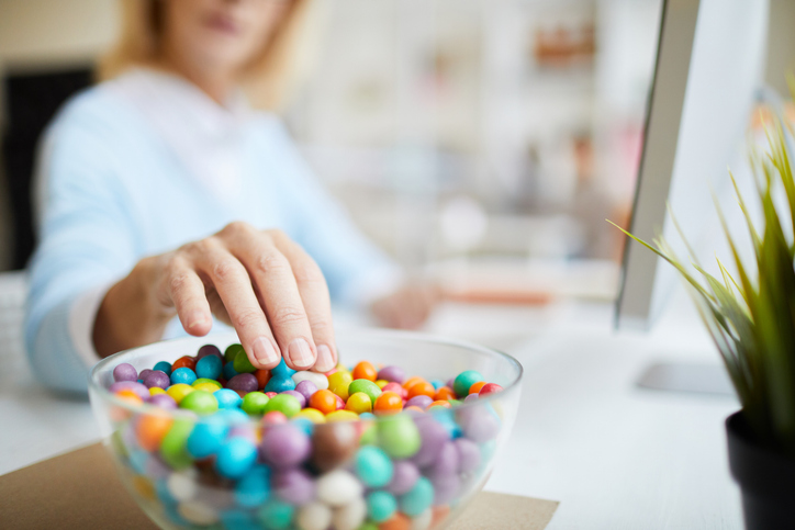 woman reaching into bowl of candy | Ozempic Foods to Avoid