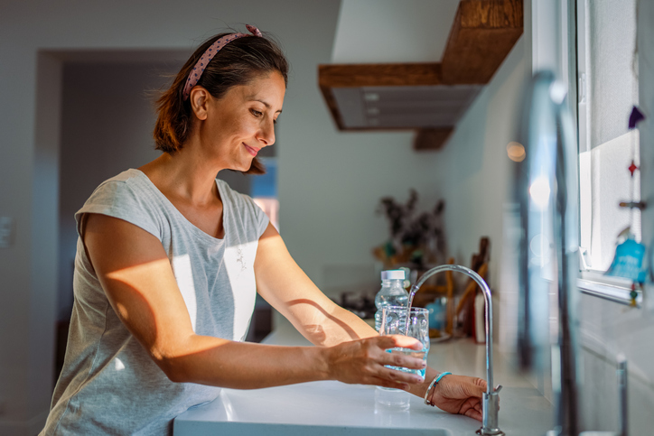 a woman pours water into a cup | Why glucose spikes are harmful