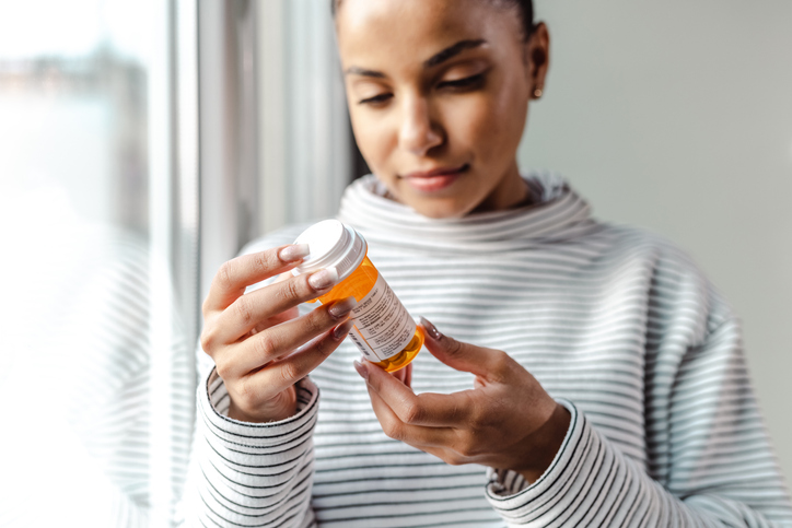 woman looking at prescription bottle | How to Reduce Night Sweats?