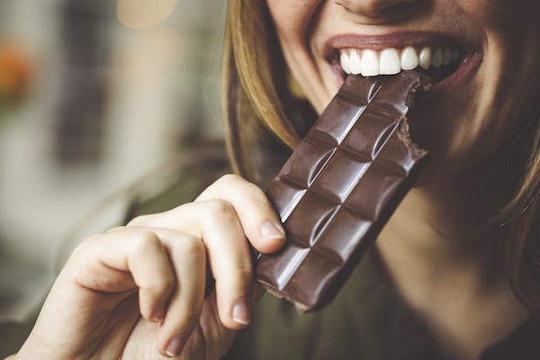 woman biting a chocolate bar | Chocolate Facts