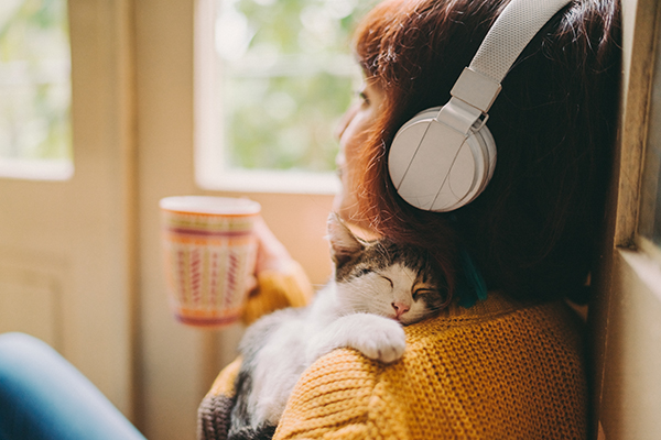 Woman listening to headphones, cuddling cat