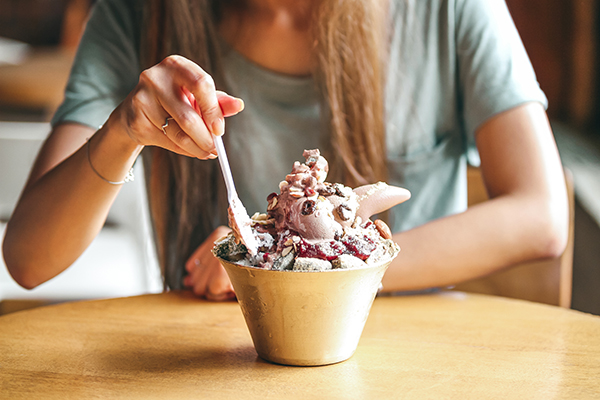 Woman eating bowl of ice cream with toppings